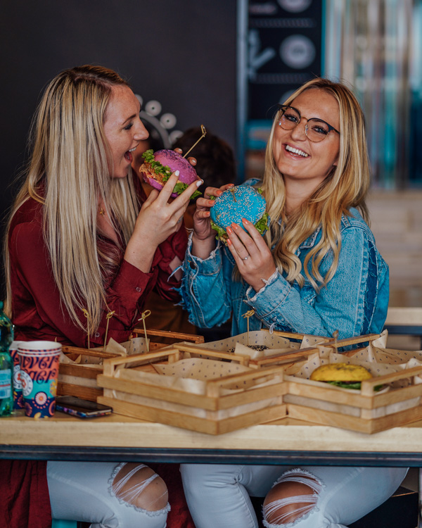 two blonde girls eating vegan burgers at flower burger in rome