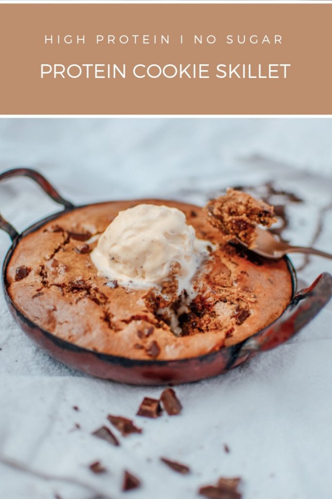 healthy chocolate chip protein cookie skillet in a pan with two spoons and one ice cream scoop
